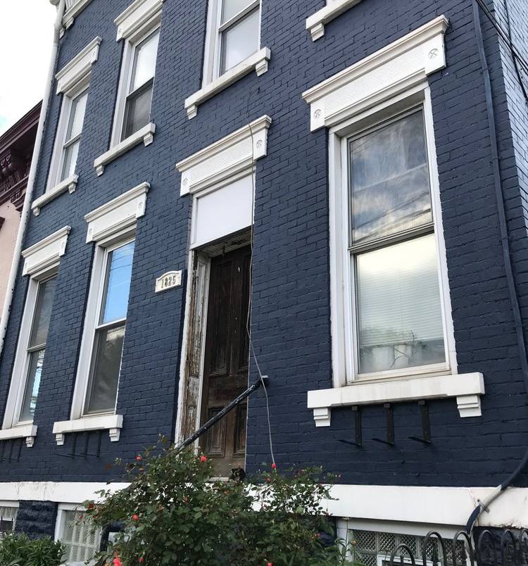 A three-storey brick townhouse painted very dark navy, with crisp white window trim and stone sills.